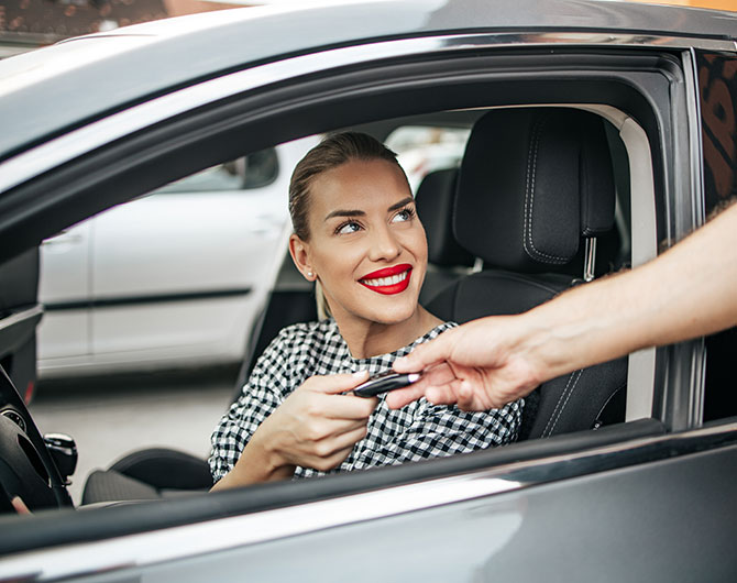 A woman accepts the keys to a rental car.