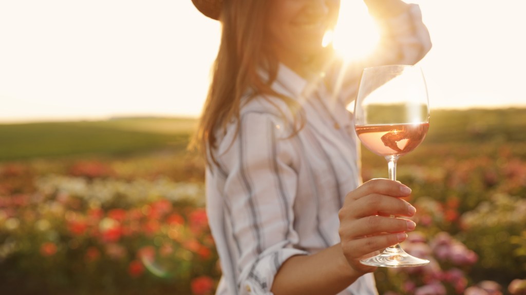 Woman,With,Glass,Of,Wine,In,Rose,Garden,On,Sunny