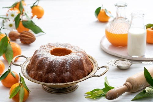 Bundt cake made of tangerine clementines baked homemade with ingredients on white