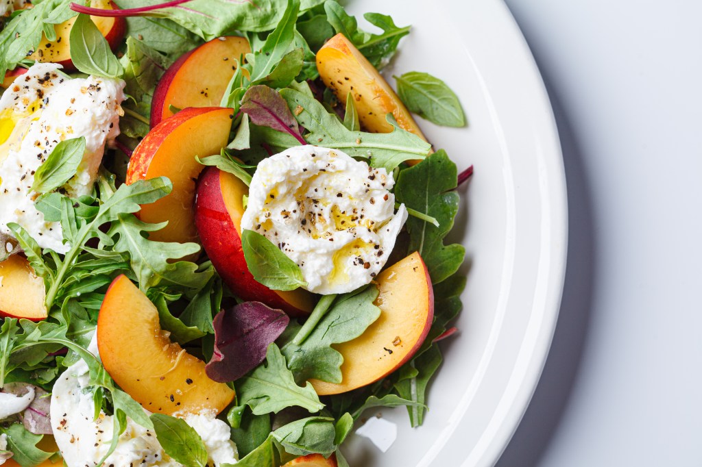 Burrata and peaches summer salad, white background.