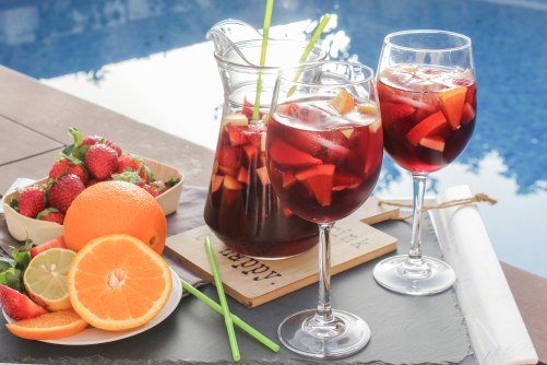 Spanish red wine (Sangria) with fruit. Strawberry, orange, Apple and banana slices. On a tray next to the pool