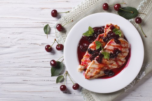 Grilled chicken with cherry sauce and mint. Horizontal top view