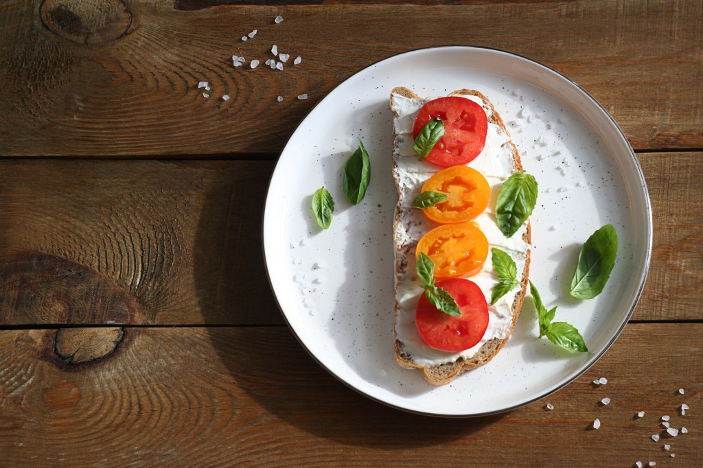 Sandwich with cheese, tomatoes and basil on a dessert plate.