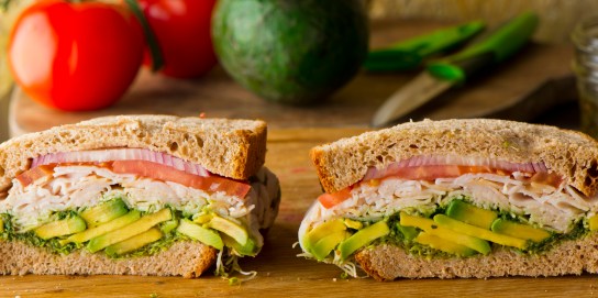 Turkey avocado sandwich. Turkey sandwich. W/ avocado slices served on toasted whole grain bread w/ Swiss cheese, onions, lettuce, tomato, mayonnaise and seasoned salt and pepper. Classic American restaurant or diner lunch sandwich favorite.